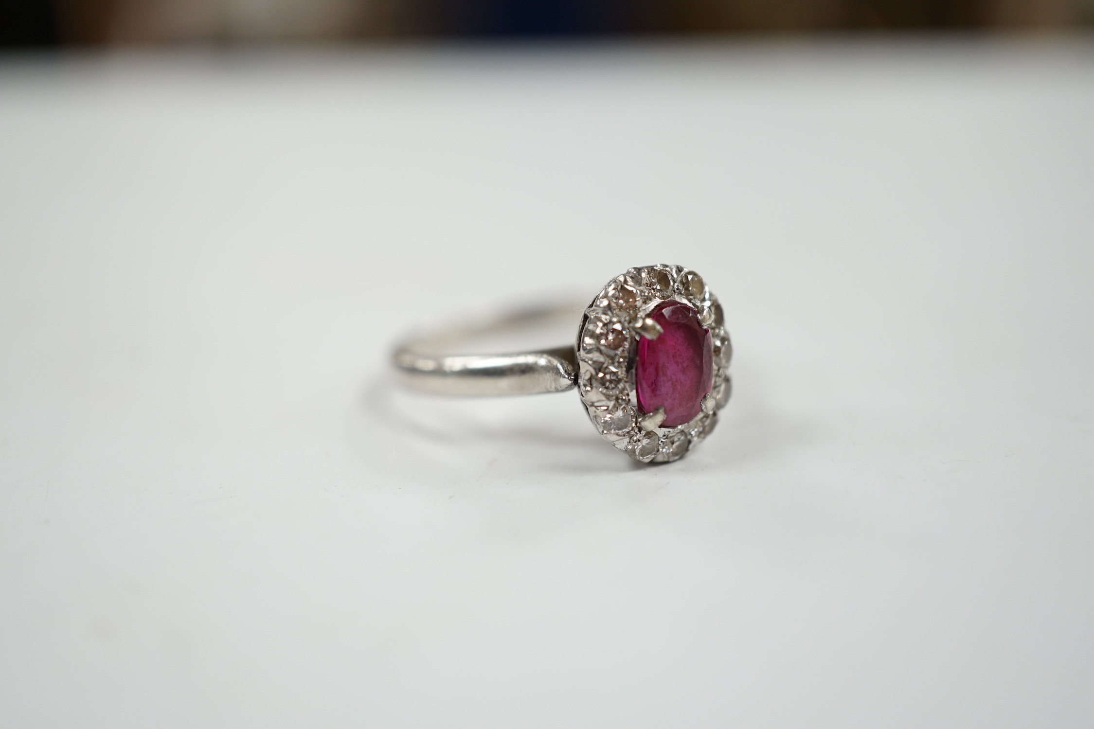 A white metal, synthetic? ruby and diamond set oval cluster ring, size P, gross weight 3.3 grams.